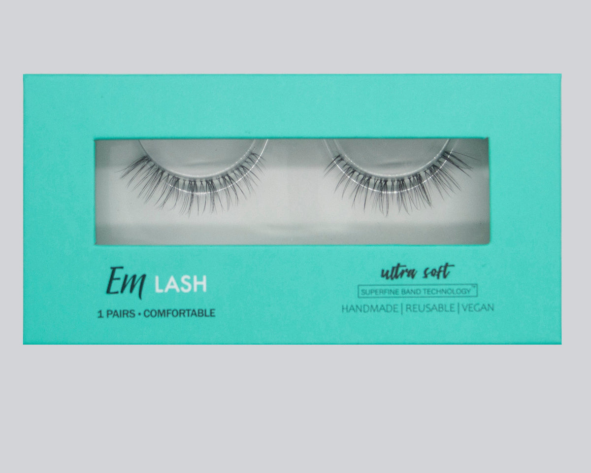 Em Lash false eyelashes in a mint green box with a clear window showing the lashes inside. The packaging features white and black text detailing the product features.