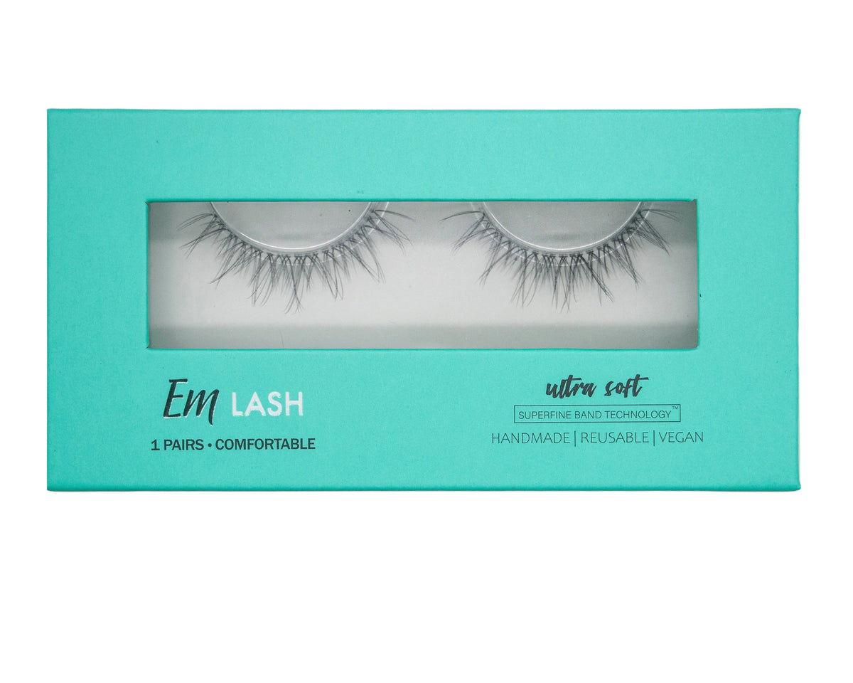 Em Lash false eyelashes in a turquoise rectangular box with a clear window showing the lashes inside, on a light gray background.