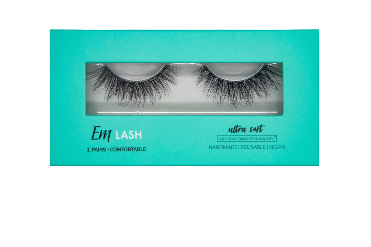 Em Lash false eyelashes in a turquoise rectangular box with a clear window showing two pairs of black lashes, on a light gray background.
