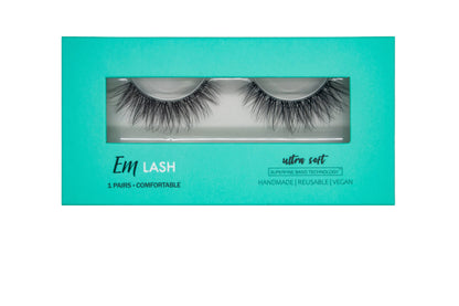 Em Lash false eyelashes in a turquoise rectangular box with a clear window showing two pairs of black lashes, on a light gray background.